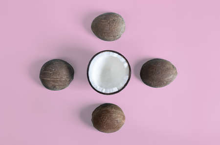 Top view of a coconut half and four smaller coconut shells on a pink background. Healthy food concept.の写真素材