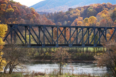 Train bridge over river, between two hills, with autumn foliageの写真素材