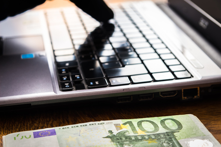 Heap of One Hundred Euro Bills next to a Laptop Keyboardの写真素材