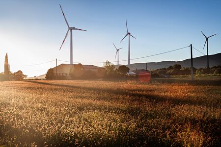 Four Wind Turbines in the Sunset in a Field and next to a Farmの写真素材