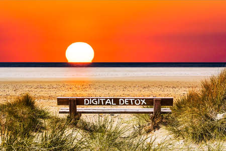 The Words Digital Detox written on a Bench with View of the Sunset at the Oceanの写真素材