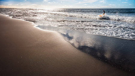 One young man surfing very relaxed on an empty beach on the Canary Islandsの写真素材