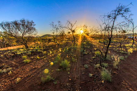 Sun rising over outback landscape and blue sky