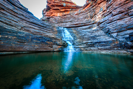 Waterfall flowing through rocky gorge with reflection in waterの写真素材