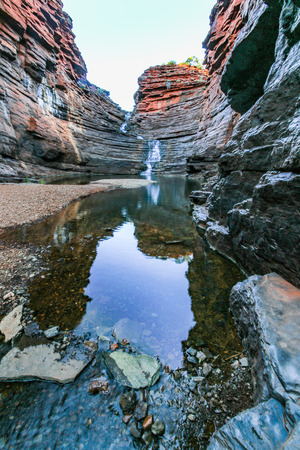 Waterfall flowing through rocky gorge with reflection in waterの写真素材