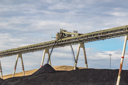 Coal mining scene showing conveyor, and black coal deposits under a wide Australian sky. Industrial...