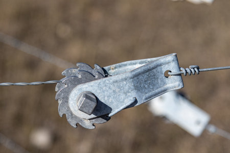Close up of a metal wire clamp on a fence in the countryside