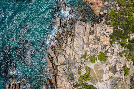 An aerial view of Rose Bay in Bowen, Queensland, reveals a stunning tropical coastline with turquoise waters, golden sand, and rocky headlands. The scene highlights coastal beauty.の写真素材
