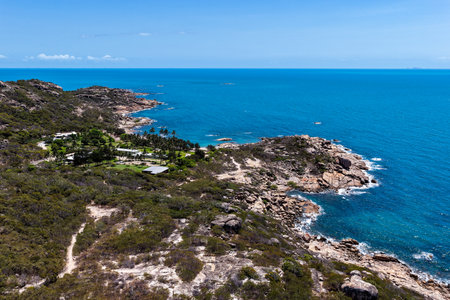 An aerial view of Rose Bay in Bowen, Queensland, reveals a stunning tropical coastline with turquoise waters, golden sand, and rocky headlands. The scene highlights coastal beauty.の写真素材