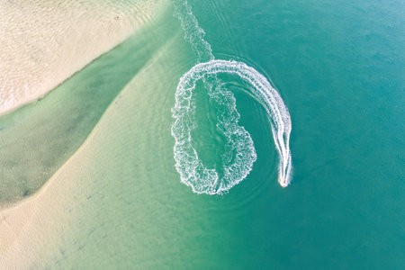 A breathtaking aerial view of jet ski riding through the lake in Forster on the Mid North Coast of New South Wales, showcasing turquoise ocean watersの写真素材