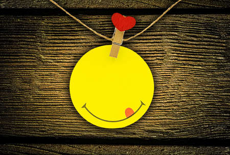 Circle yellow valentine note hanging on cord with clips with red heart head on wooden background....