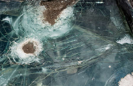 Old weathered broken bulletproof glass of car after shooting.の写真素材