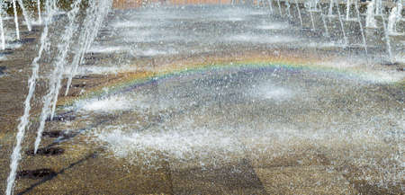 Rainbow on floor in spray of fountain.の写真素材