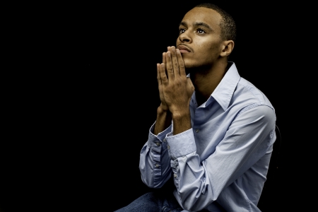 Nice isolation of a young african american black male praying with plenty of space for custom textの写真素材