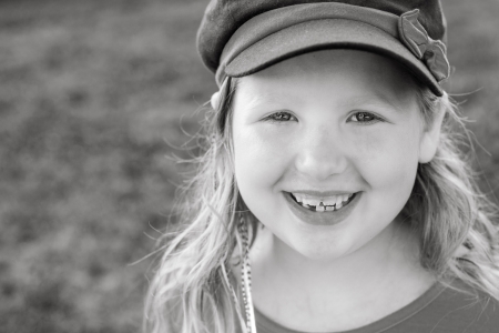 Black and white of a little girl with a large natural smile outside