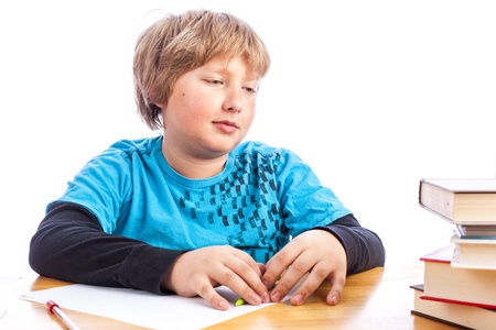 isolated young boy at a table doing homework with books. Space for custom text