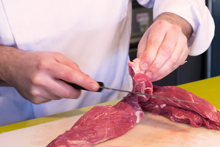 chef cutting meat on board. Carpaccio preparation.の写真素材