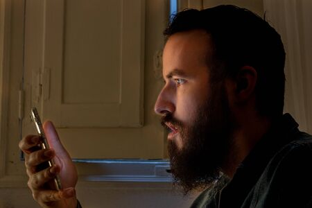 profile portrait of bearded guy looking mobile and surprised.