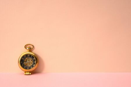Pink color background and classic golden pocket watch.の写真素材