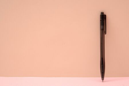 Pink color background and black ballpoint pen.