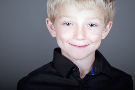 Shot of a Happy and Sweet Blonde Haired Child against Grey Background