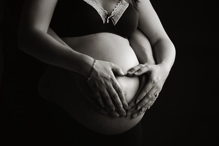 Shot of a Mother and Father Making Heart Shape on Pregnant Bumpの写真素材
