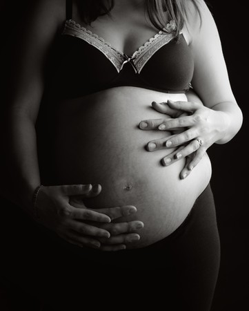 Beautiful Shot of a Mother and Father's Hands Supporting Pregnant Bumpの写真素材