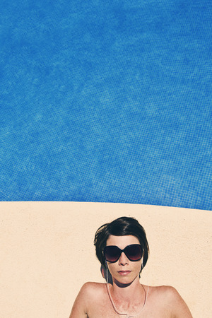 Shot of a Woman Listening to Music by the Pool