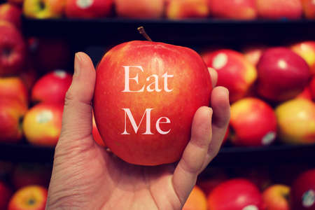 Hand holding red apple with message eat me on the appleの写真素材
