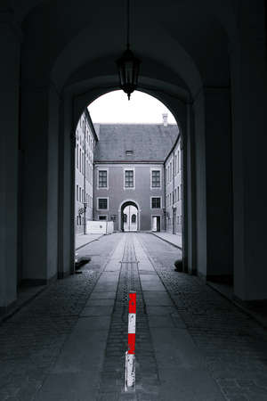 Black and white cobble stone path through archway looking at another archway.  Red and white marker in colorの写真素材