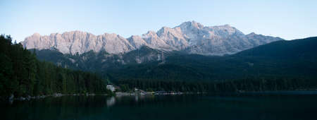 View of Zugspitze Mountains seen from bank of Lake Eibsee during late afternoonの写真素材
