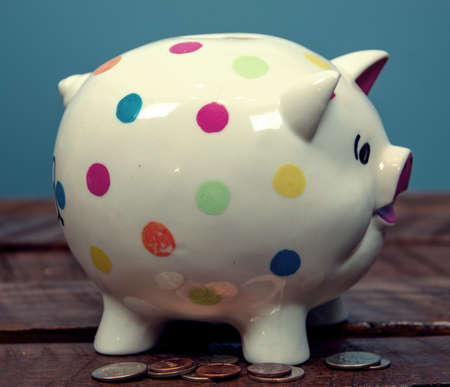 Poke a dot Piggy bank on wood table with coins around itの写真素材