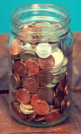 Close up on Mason glass jar filled with coins, penny, nickel, quarter, dimesの写真素材