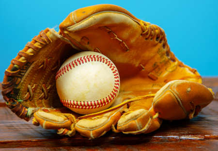 Baseball Glove with Ball in mitt on wood table with blue backgroundの写真素材