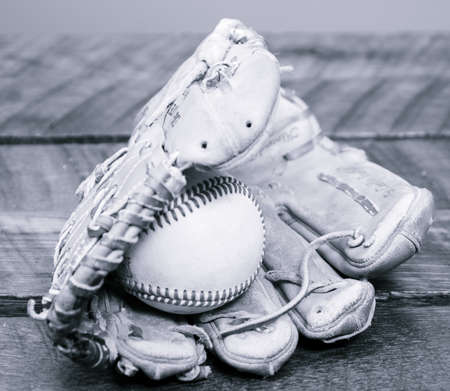 Black and white filter on Baseball Glove with Ball in mitt, laying on wood tableの写真素材