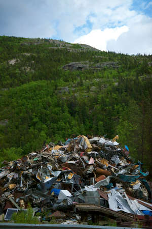 Large junk pile with scrape metal with forest behind the pile.の写真素材