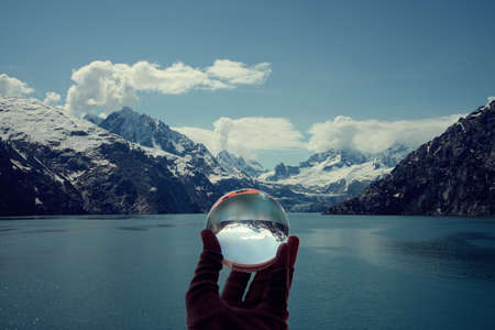 View of Glacier Bay National Park and Preserve seen in crystal ball held by a handの写真素材