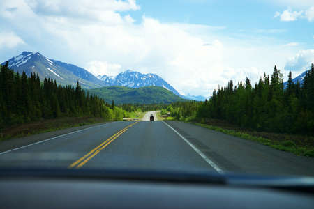 Looking out the front Car window, with pine trees, mountains, and roads in the distance.の写真素材