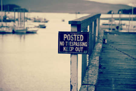Old worn sign, Posted No trespassing keep out on post for old wooden pierの写真素材