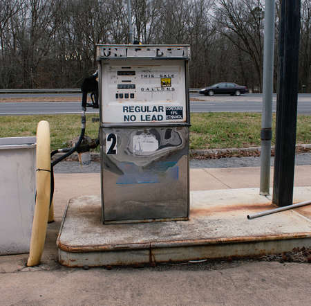Gas Pumps at abandoned Gas Station, with car on the road in background
