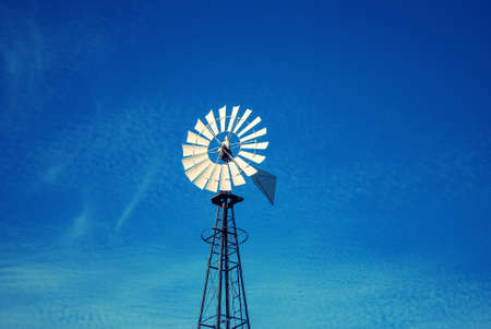 Metal vintage look windmill with blue sky and wispy cloudsの写真素材