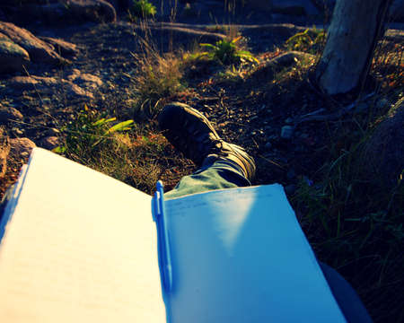 Opened hand made Journal with blank paper, laying on the ground with golden light hitting the pages.の写真素材
