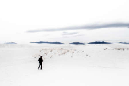 Figure in black walking along dunes in White Sands National Park in New Mexico with over overexposure dreamscape effect.の写真素材