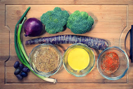 Various vegetables, spices, and sauce on a bamboo cutting board.