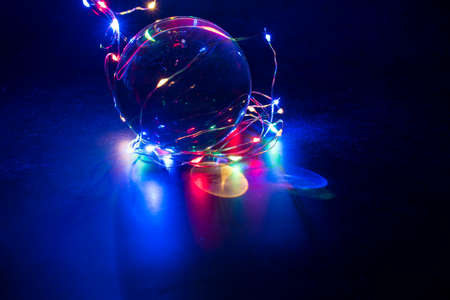 Led color lights reflected in crystal ball with dark background.