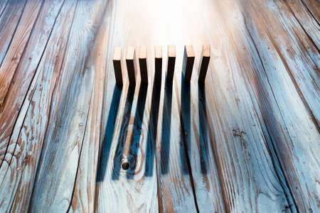 Line of dominoes standing up, with long shadows.の写真素材