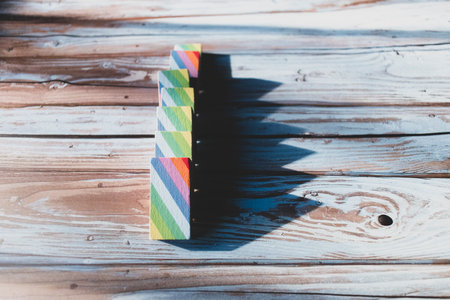 Line of seven dominoes with colorful print, fallen down on a wood table.の写真素材