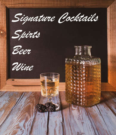 An alcoholic drink with blackberries in front of a chalkboard sign.  Advertising different types of drinks.の写真素材