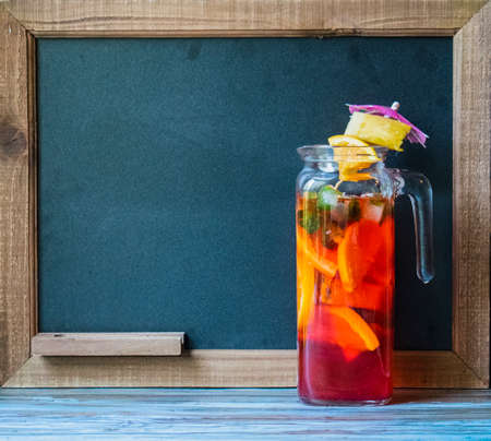 Cocktail drink in front of chalkboard for the drink menu, with tropical wood tableの写真素材