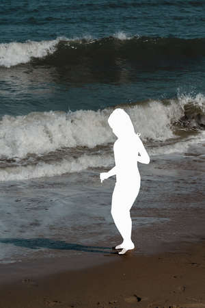 Silhouette of a young woman running on the beach in summerの写真素材